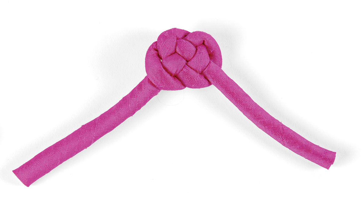 2 Mold the knot into shape. Gently coax the cord from the center out to tighten the knot, but keep it flat. Before it’s too snug, start pulling the outer edges tighter until they start curling under to shape the ball.