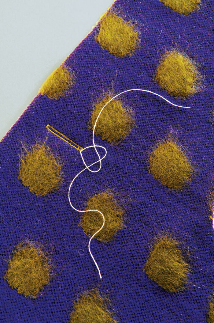 a closeup of a buttonhole sewn in a sweater knit fabric