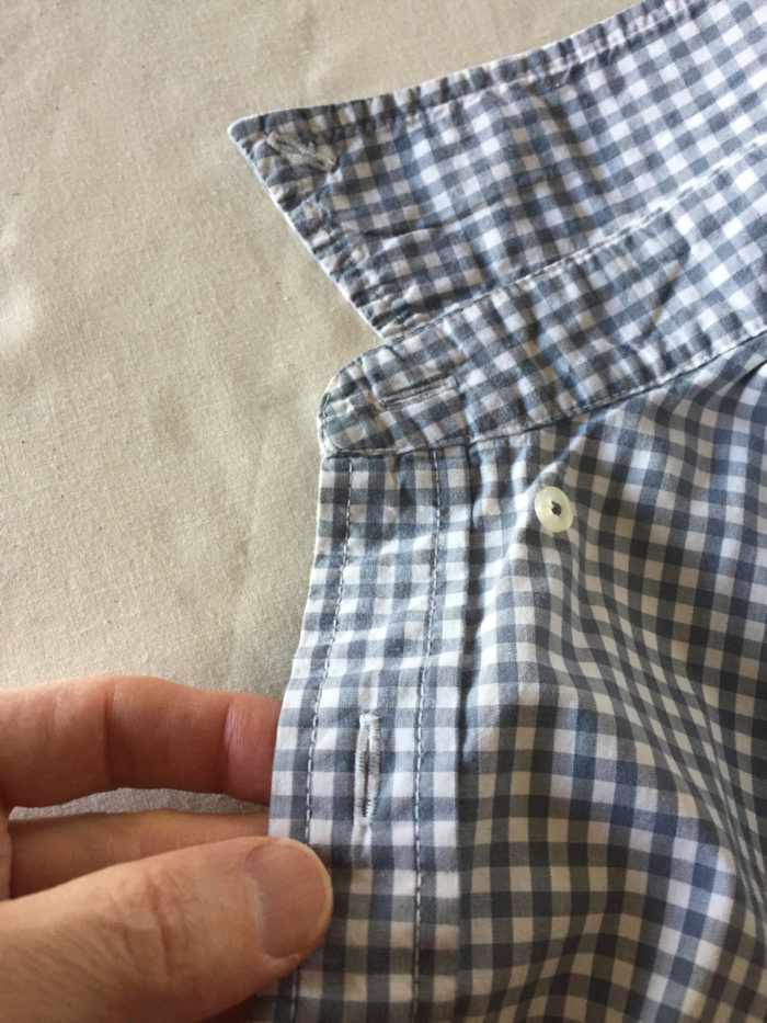 Close-up of upturned collar, collar stand and front placket on men's gray gingham shirt