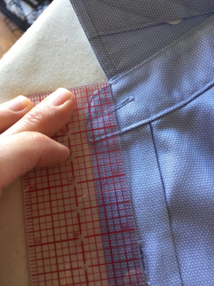 Clear ruler on top of men's RTW blue shirt shows how collar edge lines up with buttonhole on placket