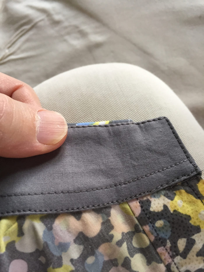 A line of edgestitching frames the entire gray undercollar on a men's shirt