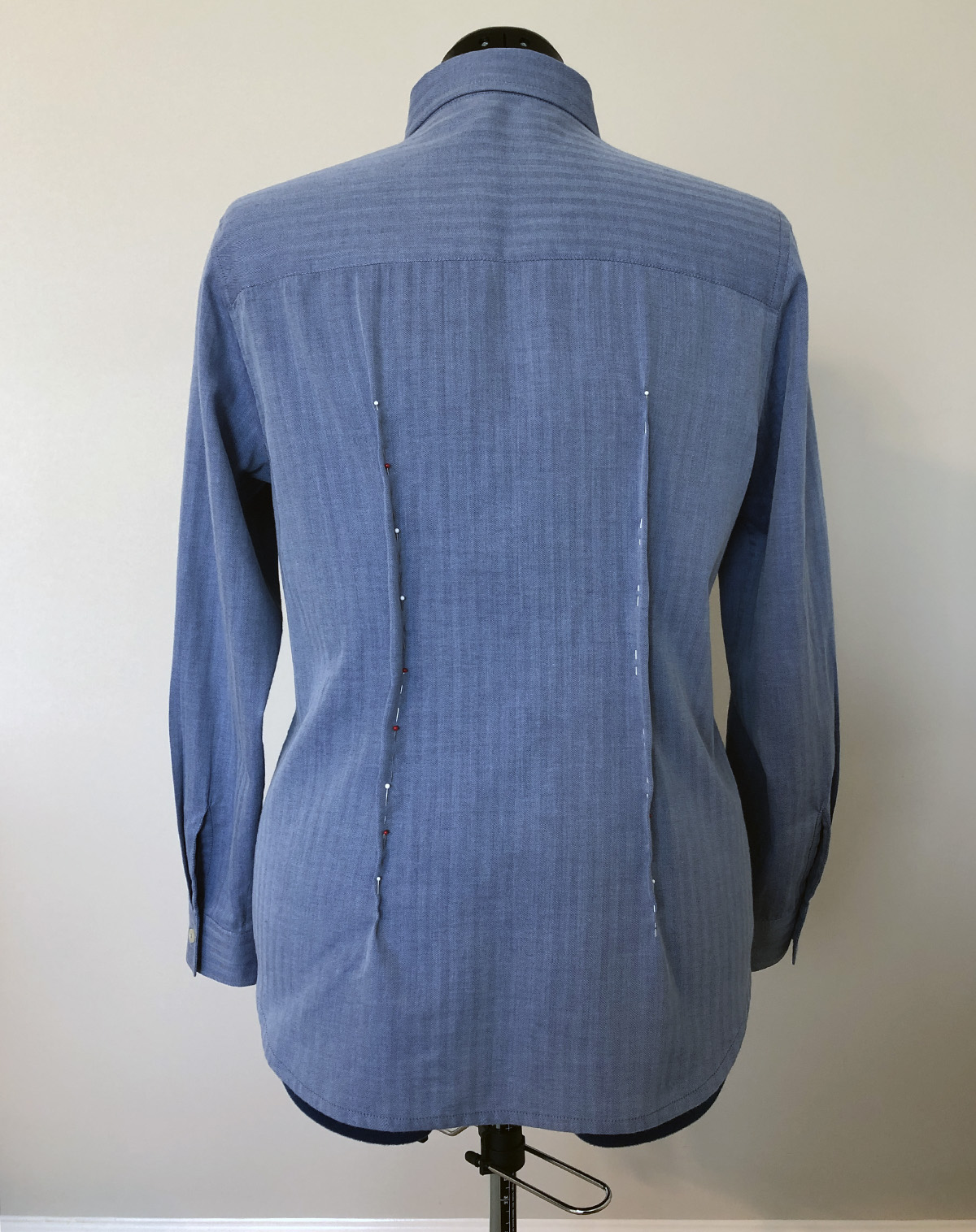 Back of blue dress shirt on dress form, with two vertical darts pinned in place