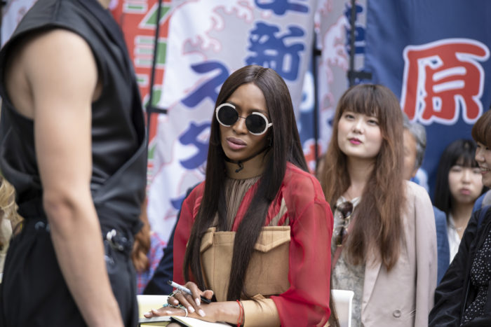 Making the Cut Judge Naomi Campbell looking at model in black streetwear outfit with Tokyo street signs as a backdrop