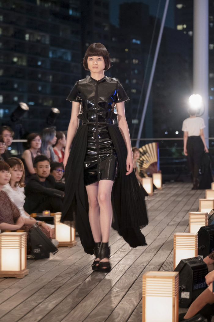 Model wearing shiny black dress on the runway