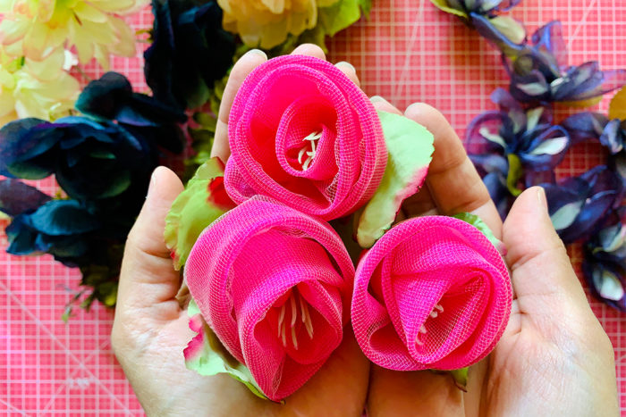 Three hot pink fabric roses held in cupped hands