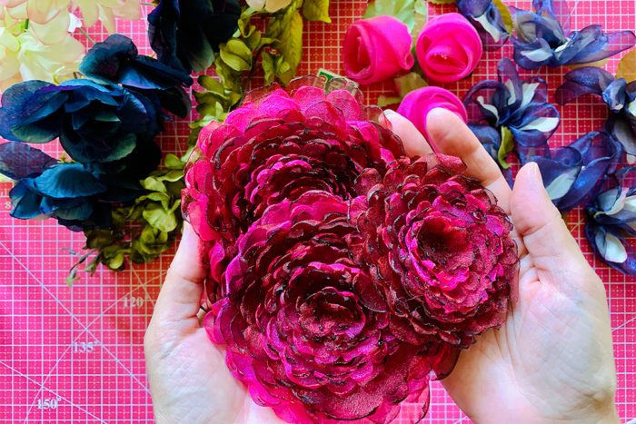 Three multilayered pink fabric peonies held in cupped hands