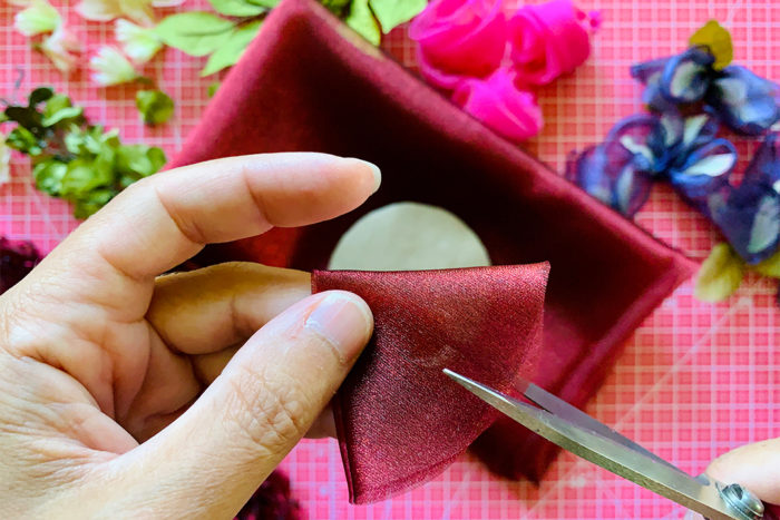 Scissors cutting into a sheer fabric circle that is folded into a quarter circle