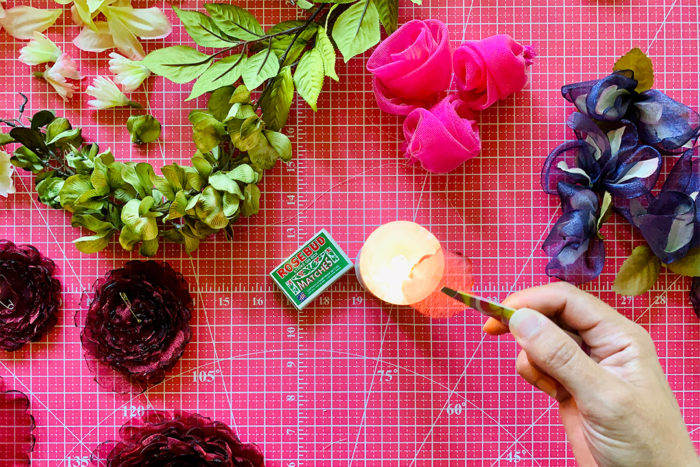 Sheer fabric circle held over a lit candle with the help of tweezers