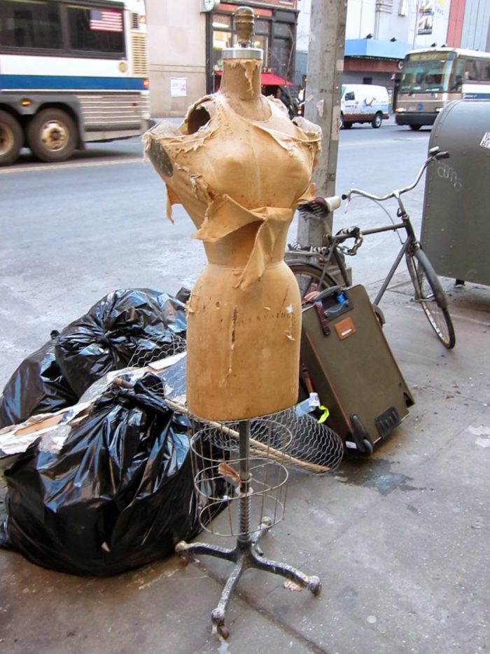 Discarded, worn, and torn dress form left at the curb with the garbage