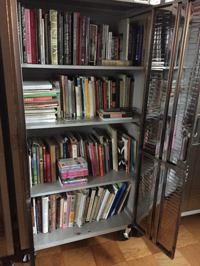 This photo is a metal cabinet filled with sewing and fashion-related books