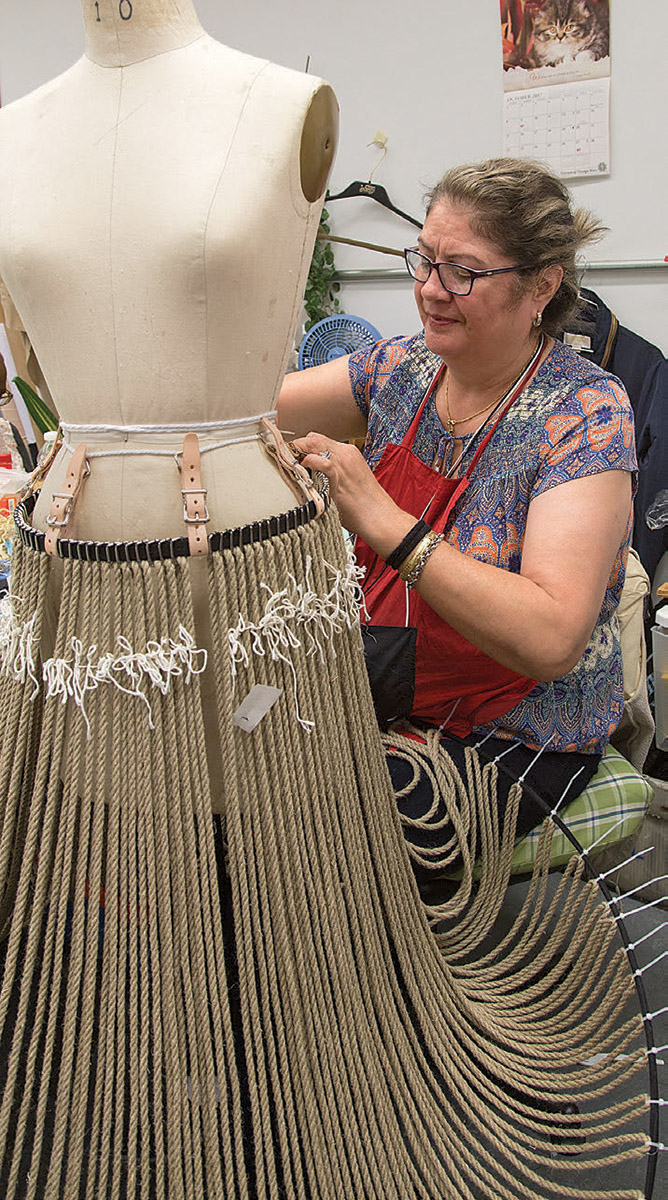 Woman working on a grasslands skirt for The Lion King.