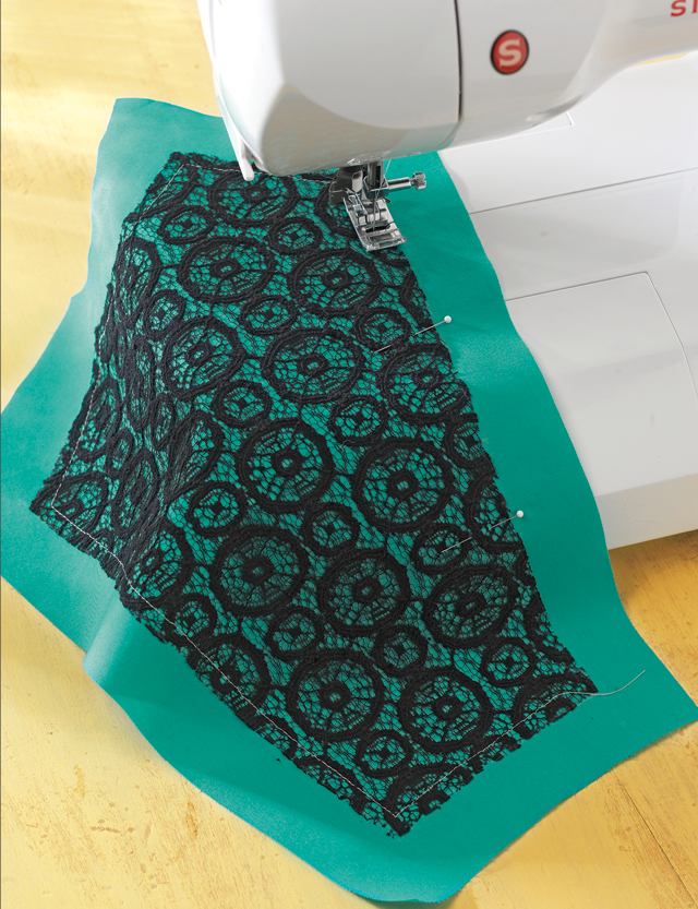 Lace panel and green fabric section being sewn on a sewing machine