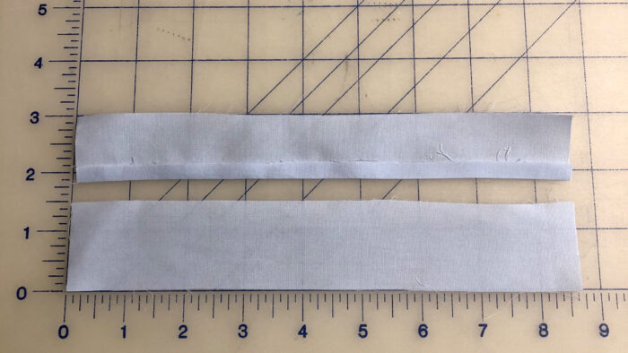 Two continuous sleeve plackets lying on gridded cutting mat