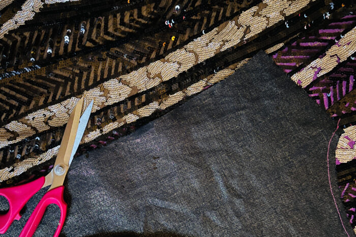 Sequined fabric and metallic linen being cut for a New Year's Eve dress