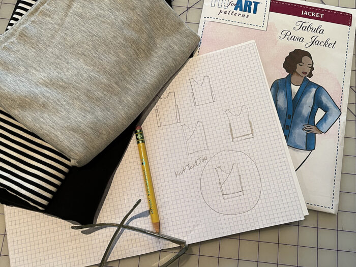 Fit for Art Patterns Tabula Rasa Jacket envelope and sketches, plus fabric, lying on gridded cutting mat