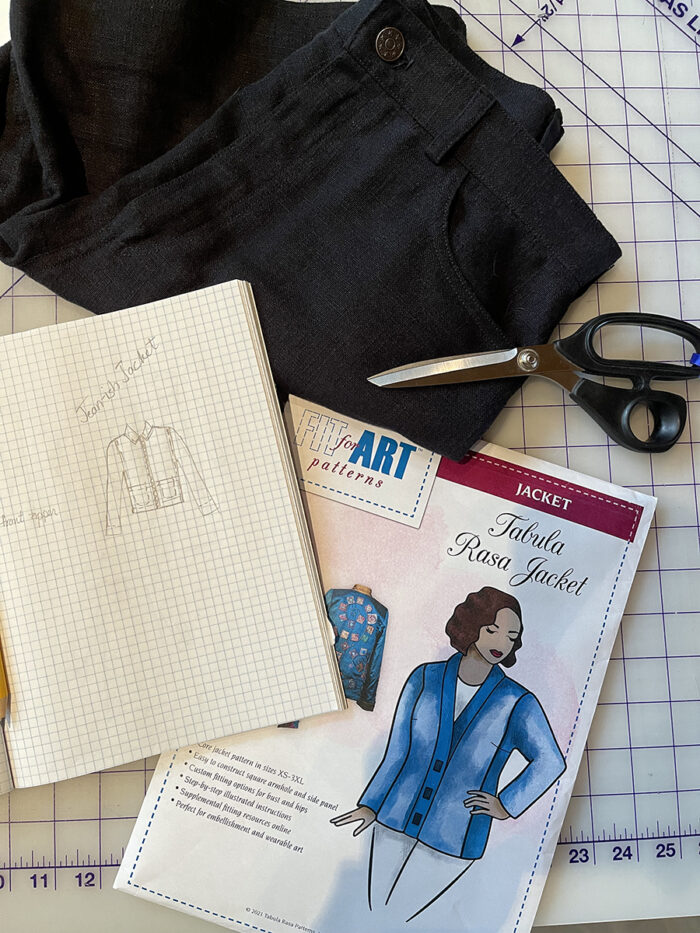 Fit for Art Pattern Tabula Rasa Jacket envelope, black jeans and scissors on a gridded cutting mat