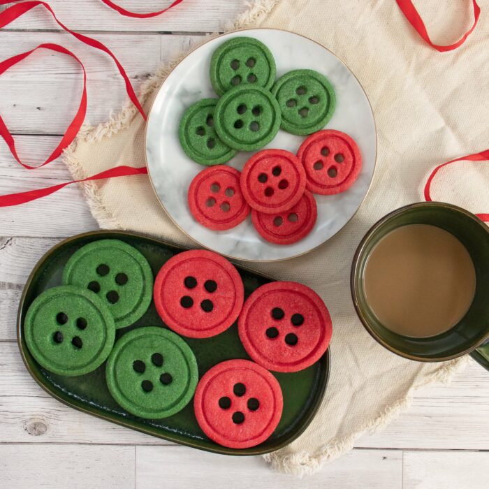 Red and green button-shaped cookie served on two plates at a party