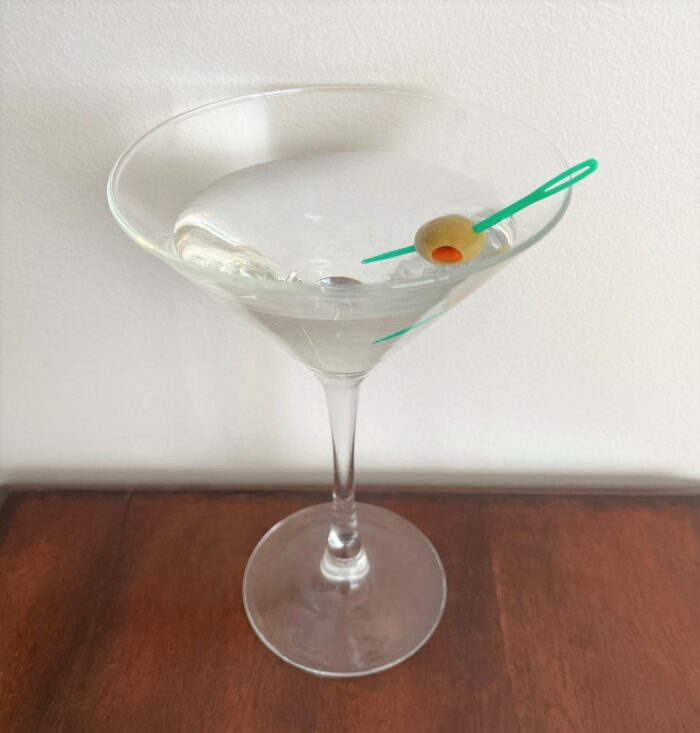 Sewing-themed party cocktail with plastic needle piercing an olive