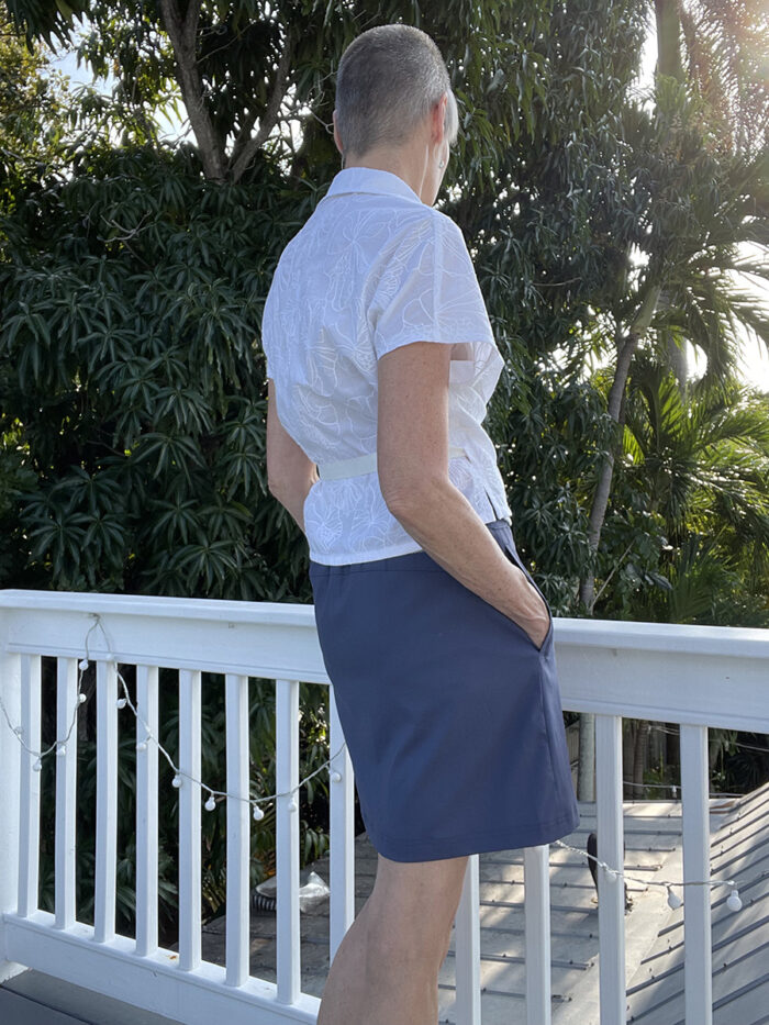 Becky Fulgoni overlooking a deck railing while wearing a white wrap top 