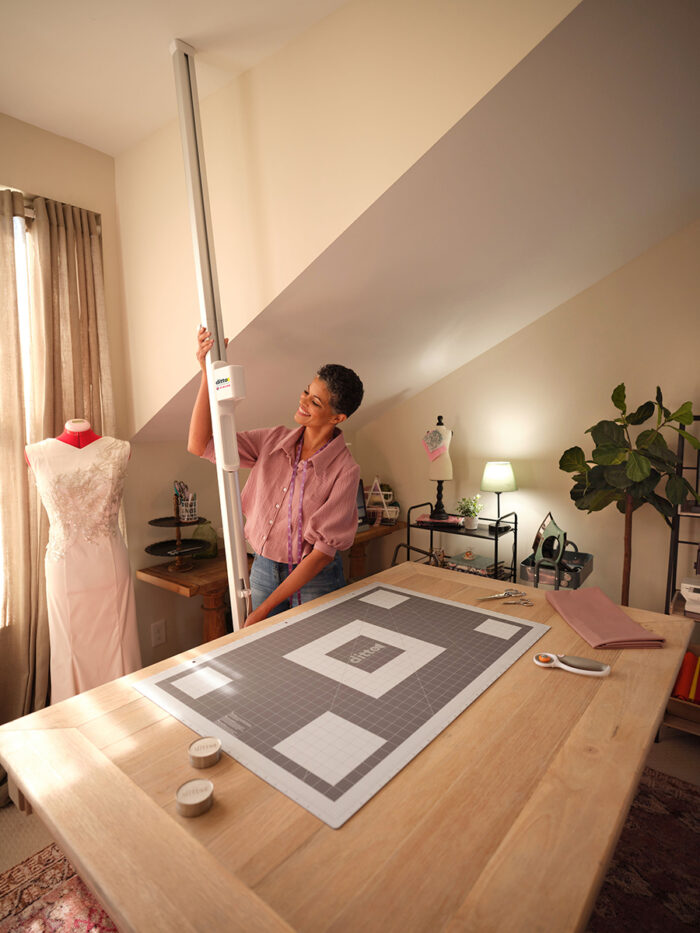 Woman installs a mounting beam while cutting mat lies on a table in the foreground