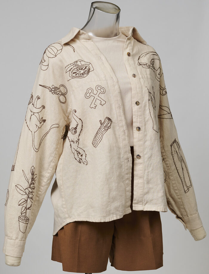 Embroidered top as overshirt with brown shorts and tee underneath on dress form