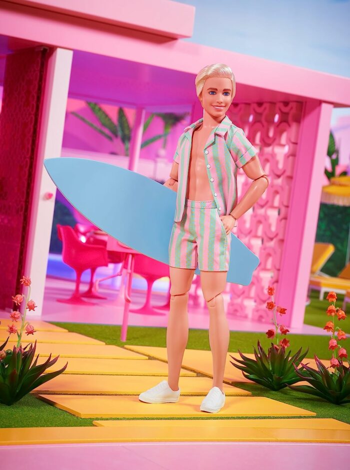 Ken doll in striped camp shirt and shorts wearing sneakers and holding a blue surfboard