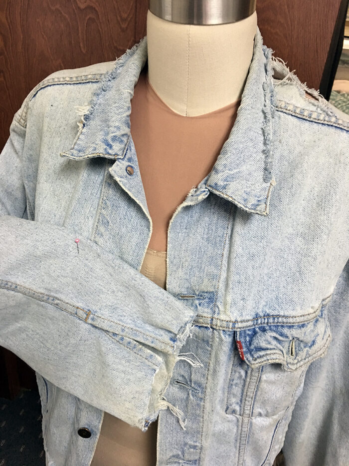 Front of tattered denim jacket on a dress form